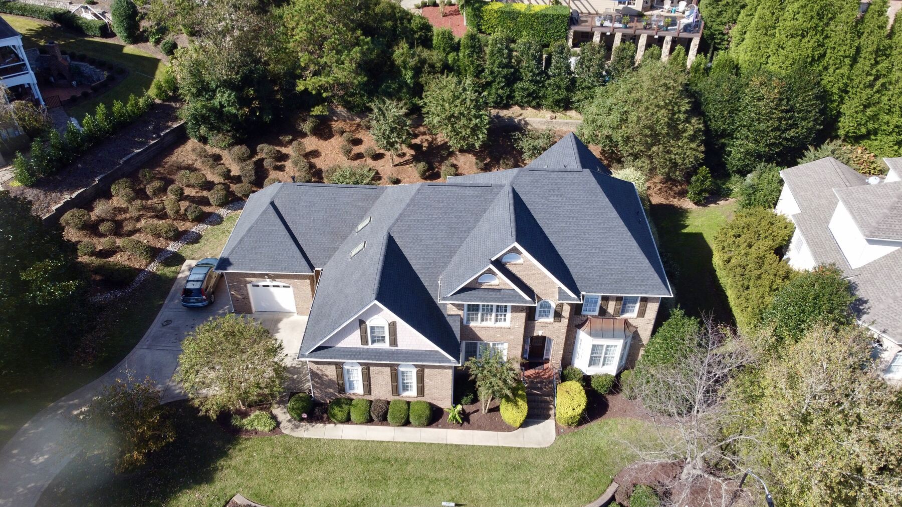 Aerial view of a completed architectural shingle roof on a brick home